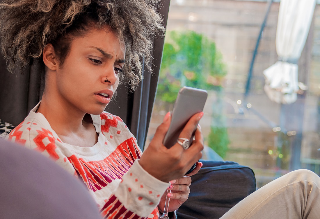 woman with worried expression looking at phone screen