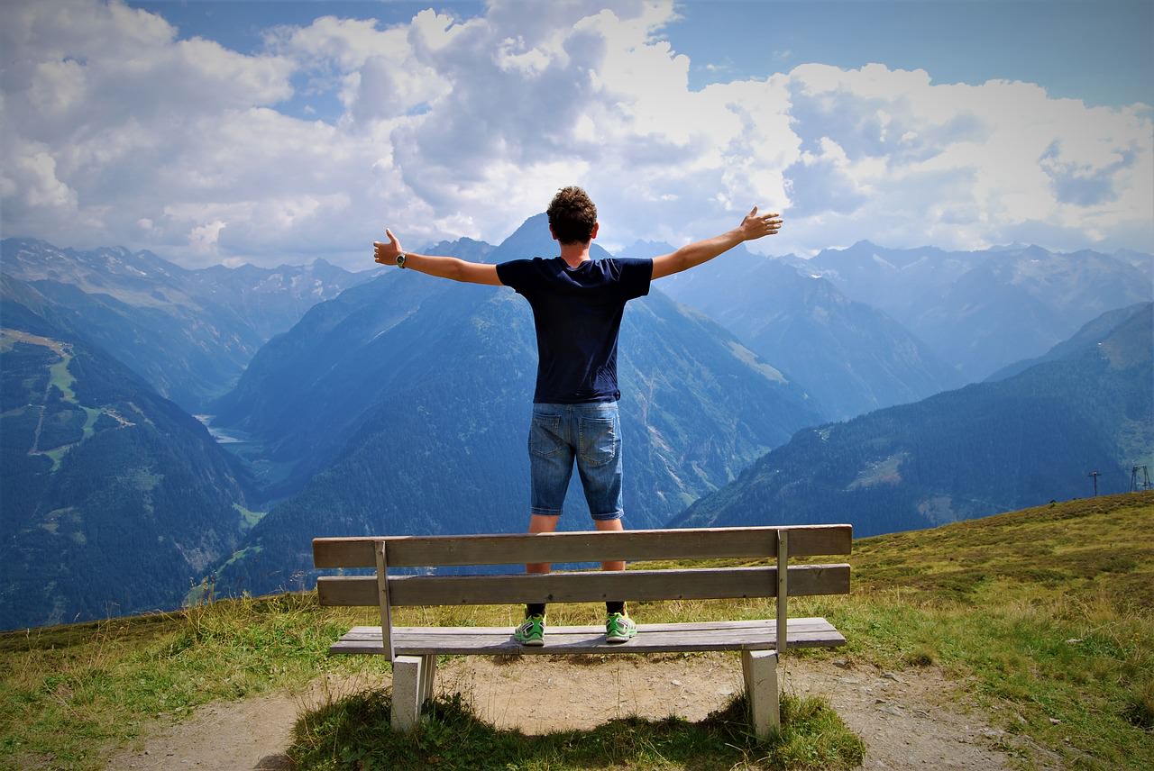 young man with arms wide at scenic overlook
