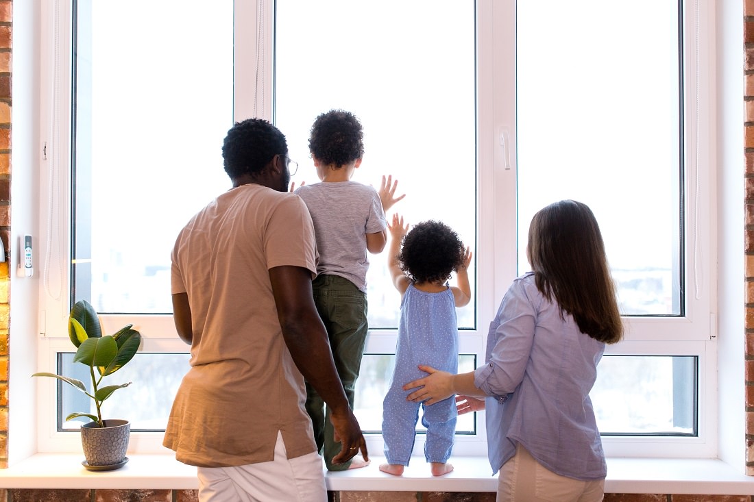family of four looks out apartment window