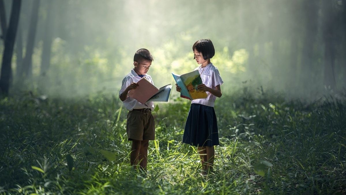 boy and girl reading books in forest
