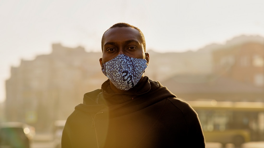 African-American man wearing mask in smoggy city
