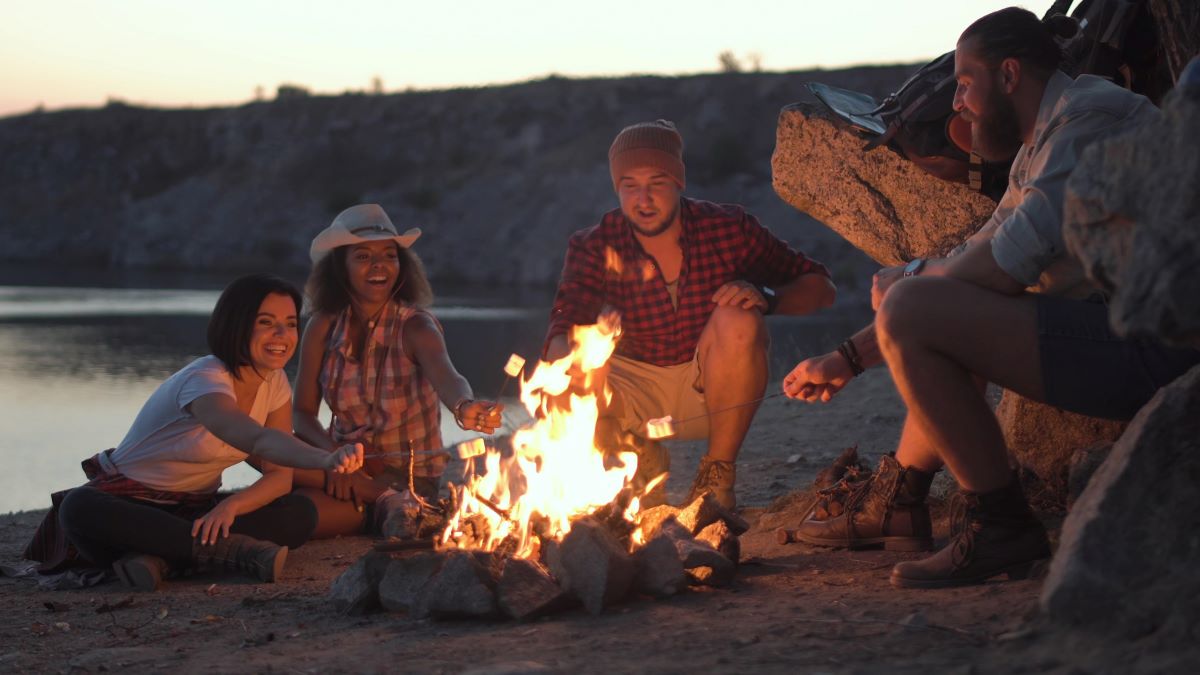 Young adult friends relaxing around a campfire