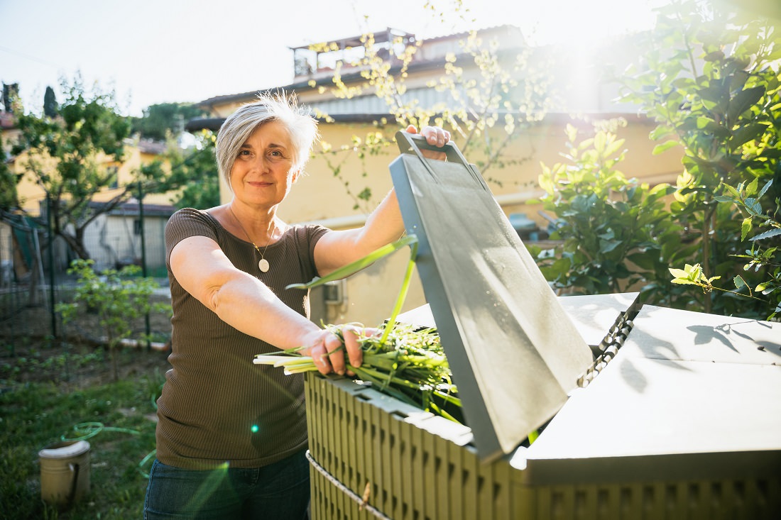 Woman placing organic waste in her compost bin