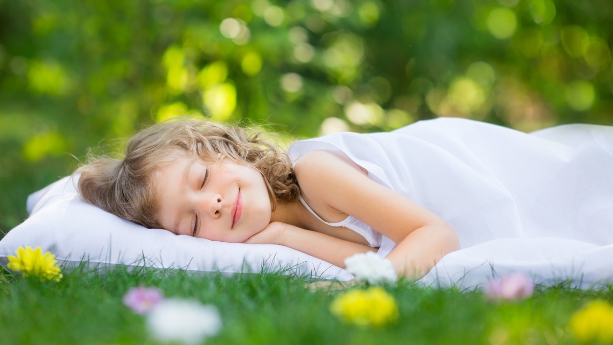 young girl sleeping on green grass