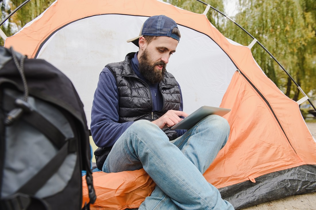 young man using iPad at camp site