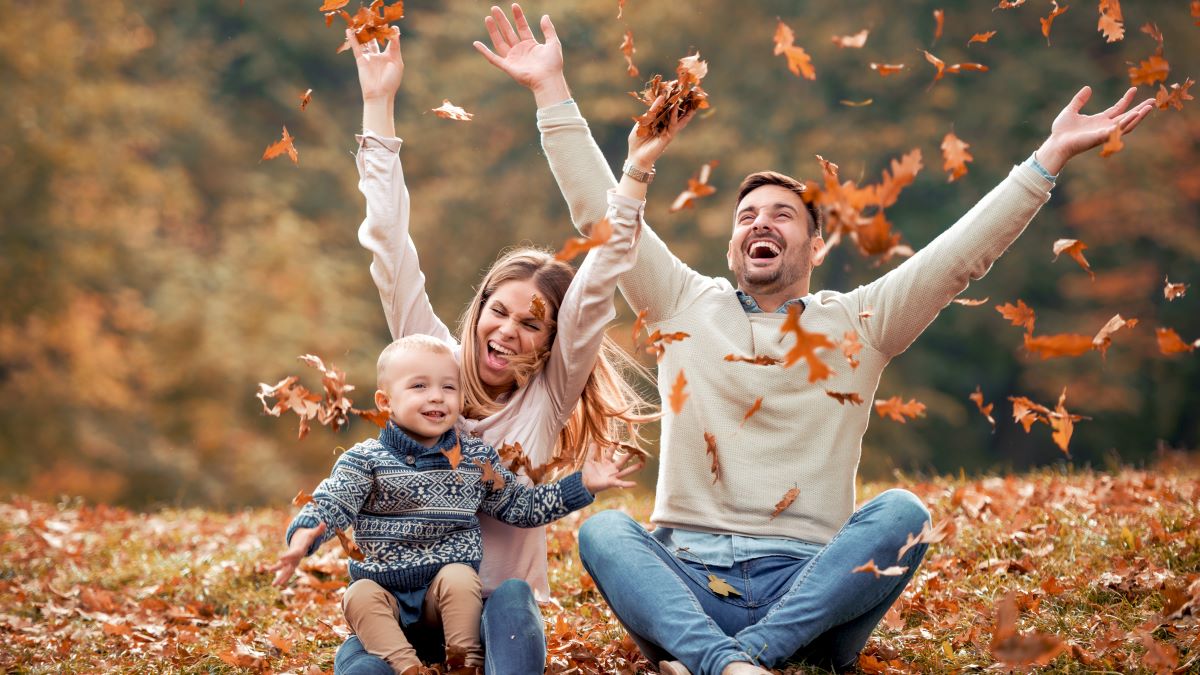 Happy family playing with leaves in beautiful autumn park.