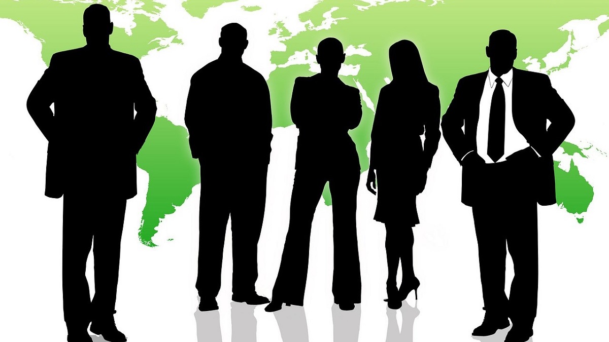 silhouettes of business people in front of green world map
