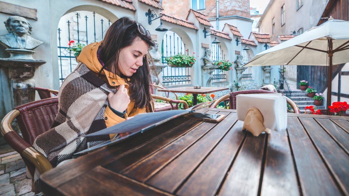 young woman reading menu at cafe outdoor table