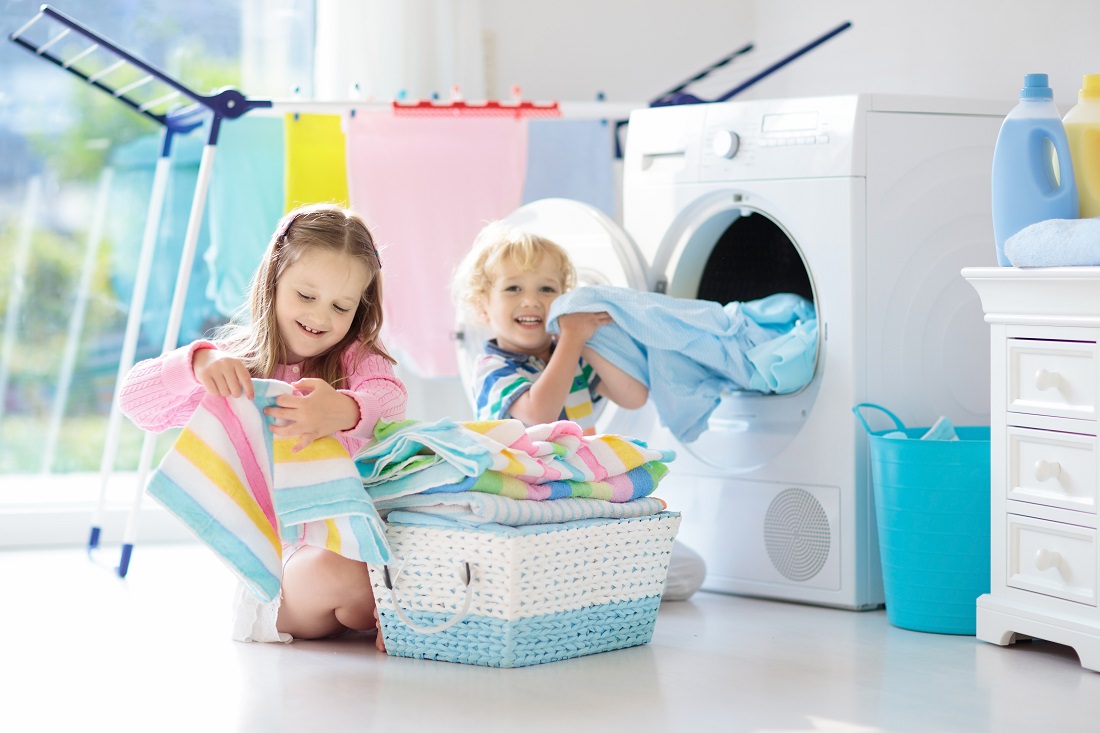 kids in laundry room folding clean clothing