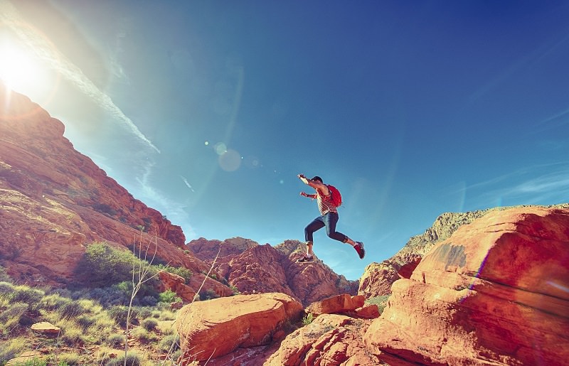 hiker leaping between rocks in natural desert area