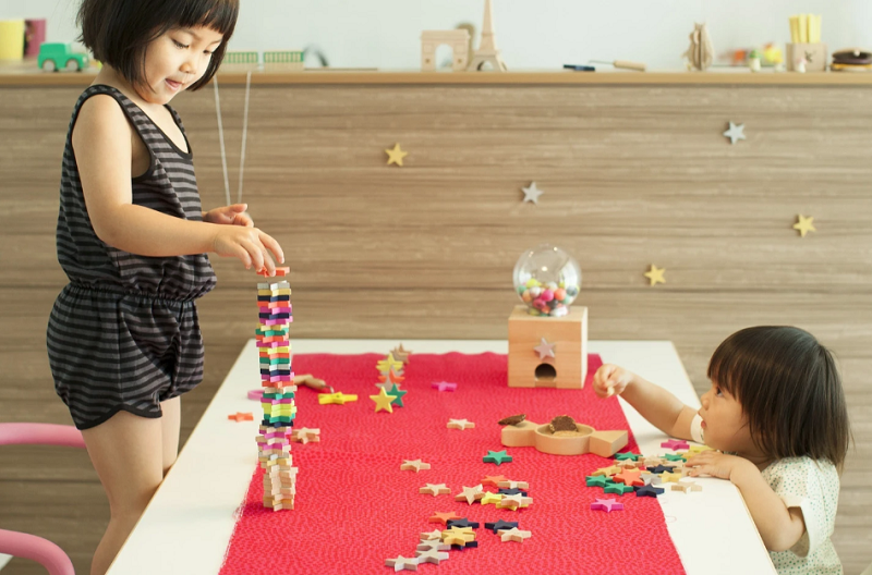 Two young girls playing with wooden star dominos