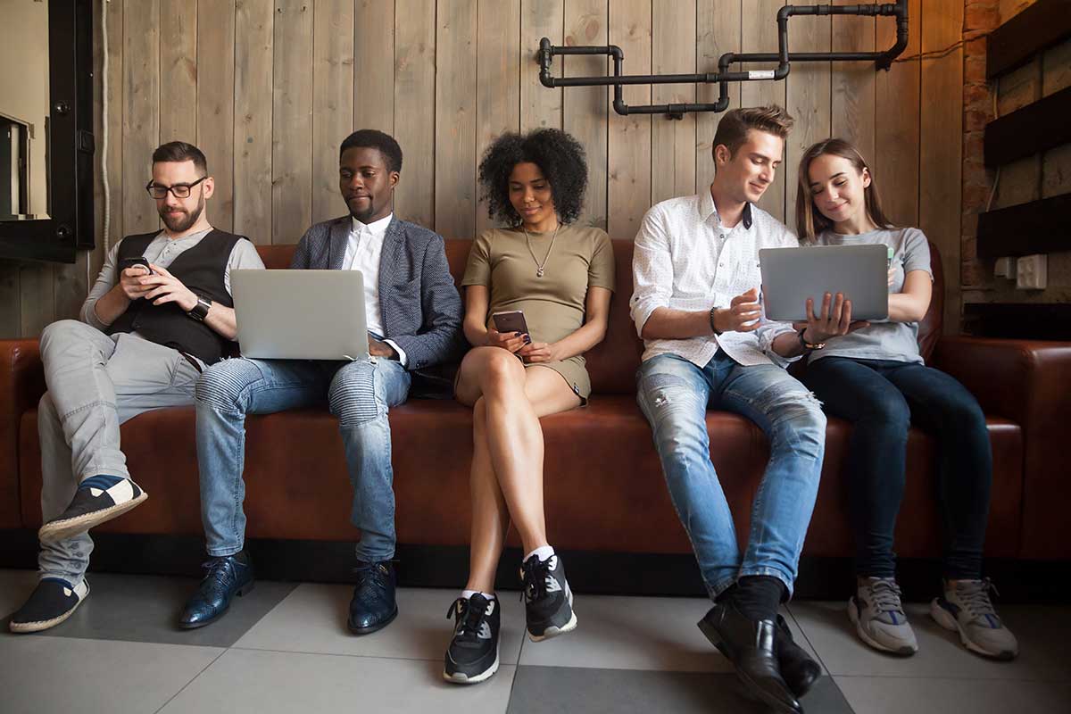 Group of diverse young adults looking at computer screens