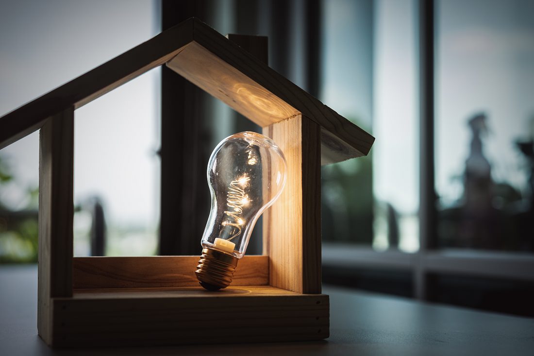 Light bulb in wood frame depicting a house, home energy concept