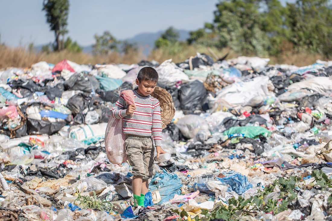 Asian boy gathering plastic for recycling from garbage heap