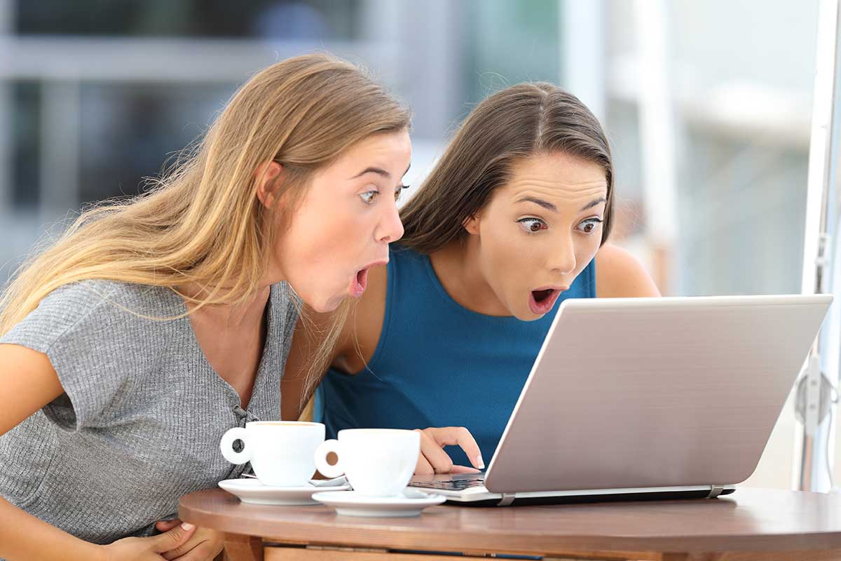 Two young women looking at laptop screen with surprised looks