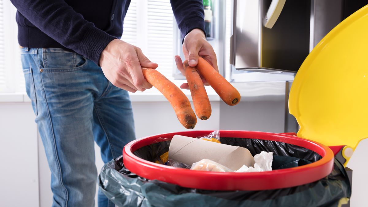 Man throwing carrots in trash