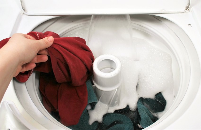putting clothes into top-loading clothes washer