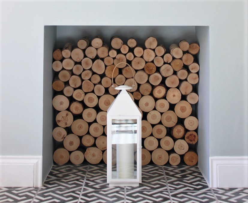 blocked off fireplace filled with cut wood and decorative lantern
