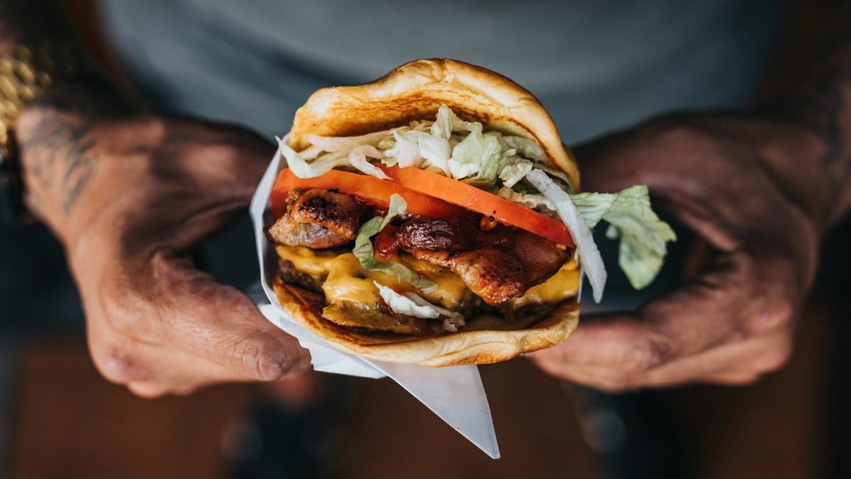 A man's hands holding a hamburger