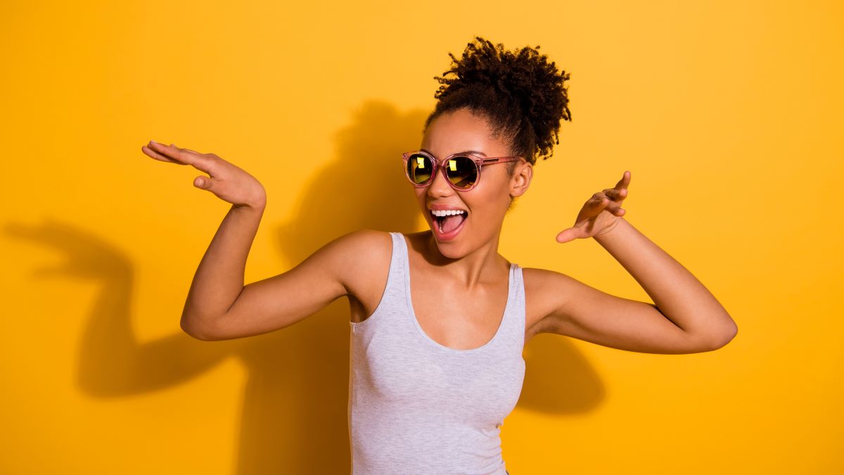 Happy young woman in sunglasses dancing