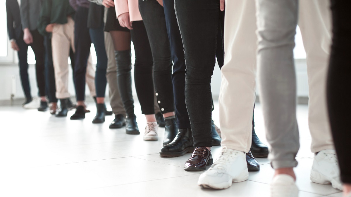 View of the shoes of young adults standing in line.