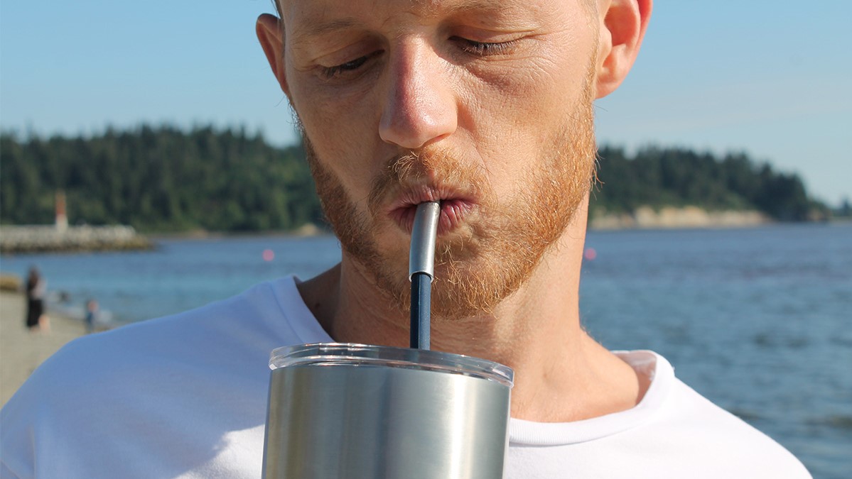 Man sipping a drink through a nOcean Wearable Reusable Silicone Straw