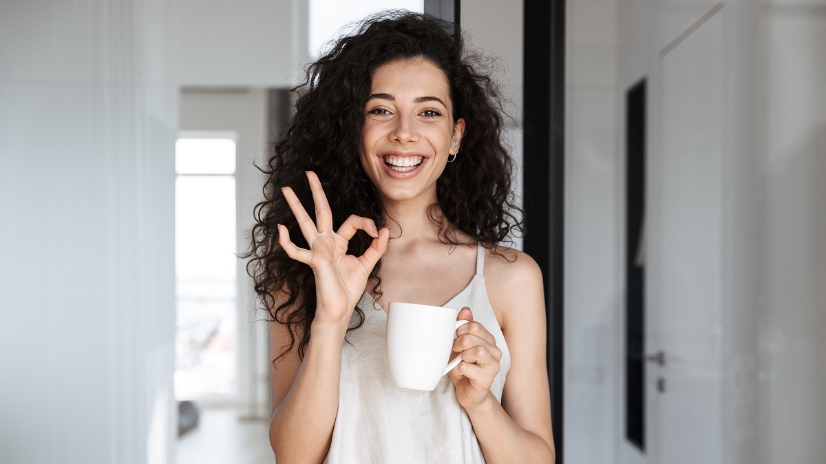 Young woman with morning tea smiling at camera