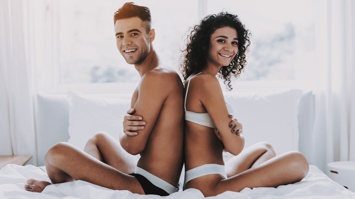 young couple sitting in underwear on bed