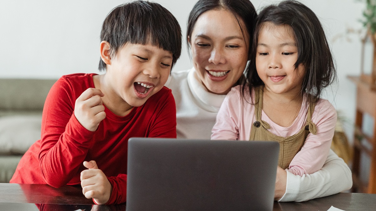 Mother and children laughing at something on laptop