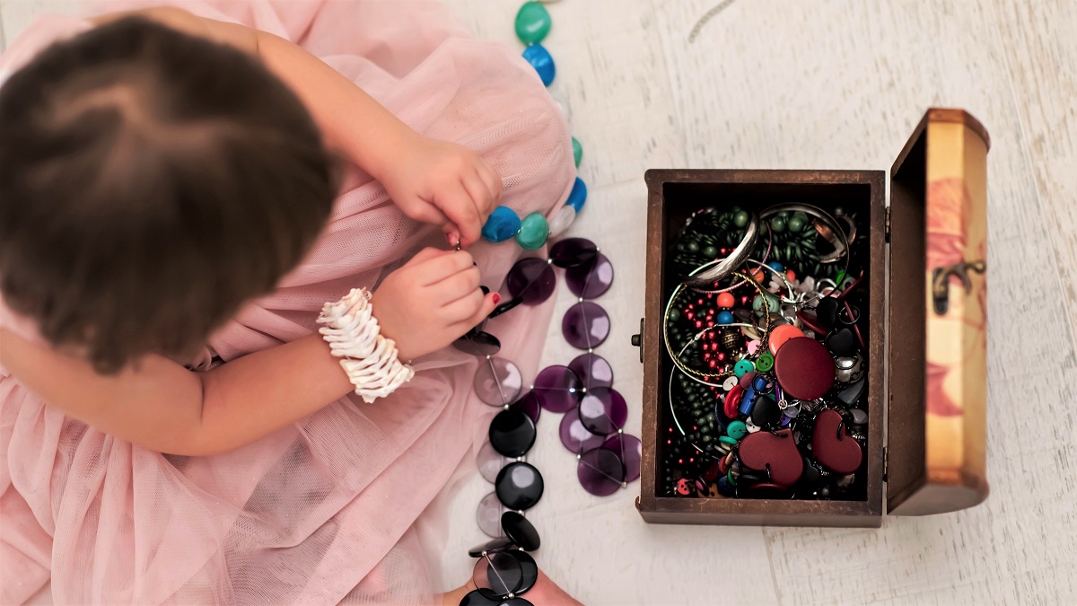 little girl playing with costume jewelry