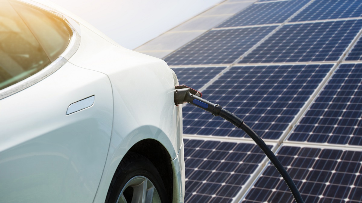 electric vehicle charging in front of solar panels