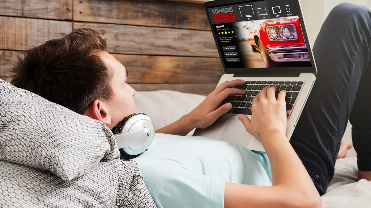 Man watching streaming video while lying on a bed.
