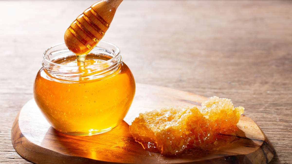 Honey in a jar, next to a honeycomb