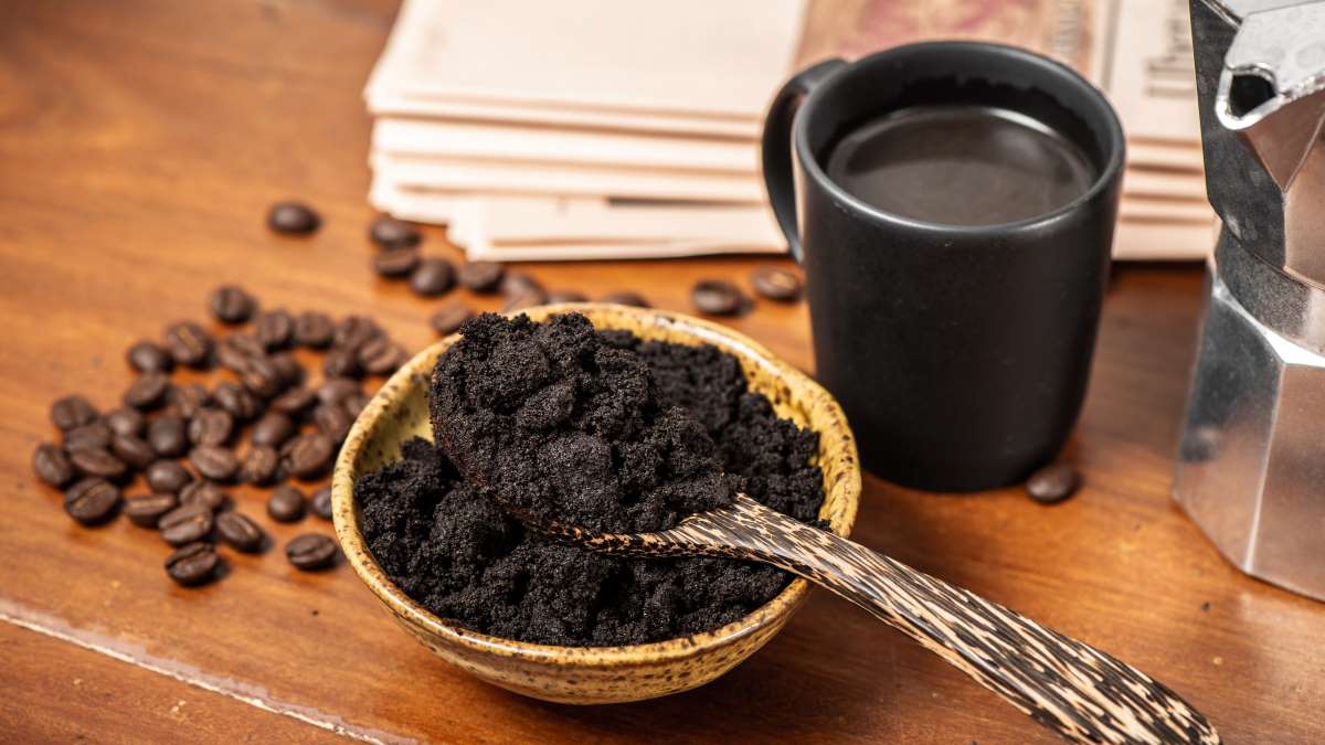 bowl of spent coffee grounds next to cup of coffee