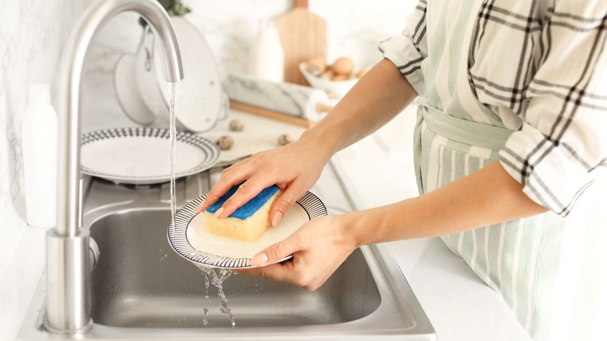 Close-up of woman's hands washing dishes in kitchen sink
