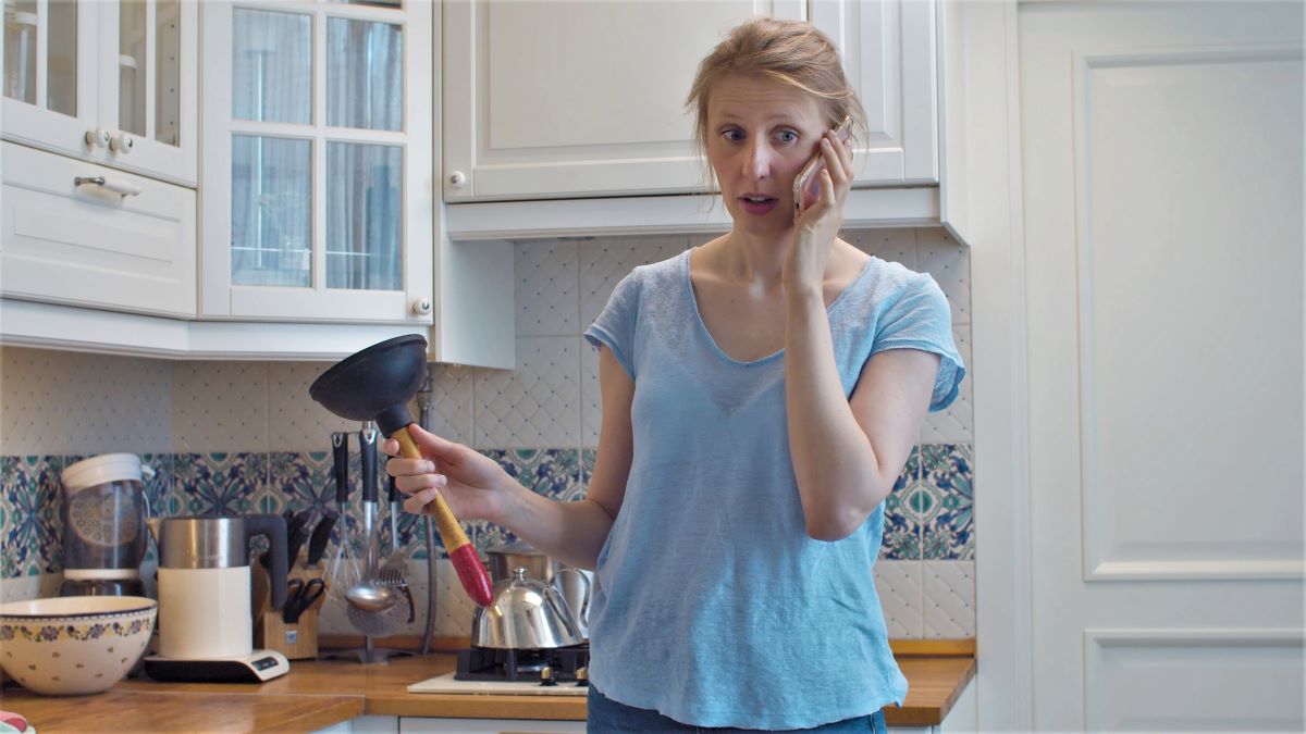 woman holding plunger calling plumber