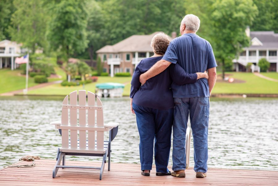 mature couple with arms around each other looking at lake