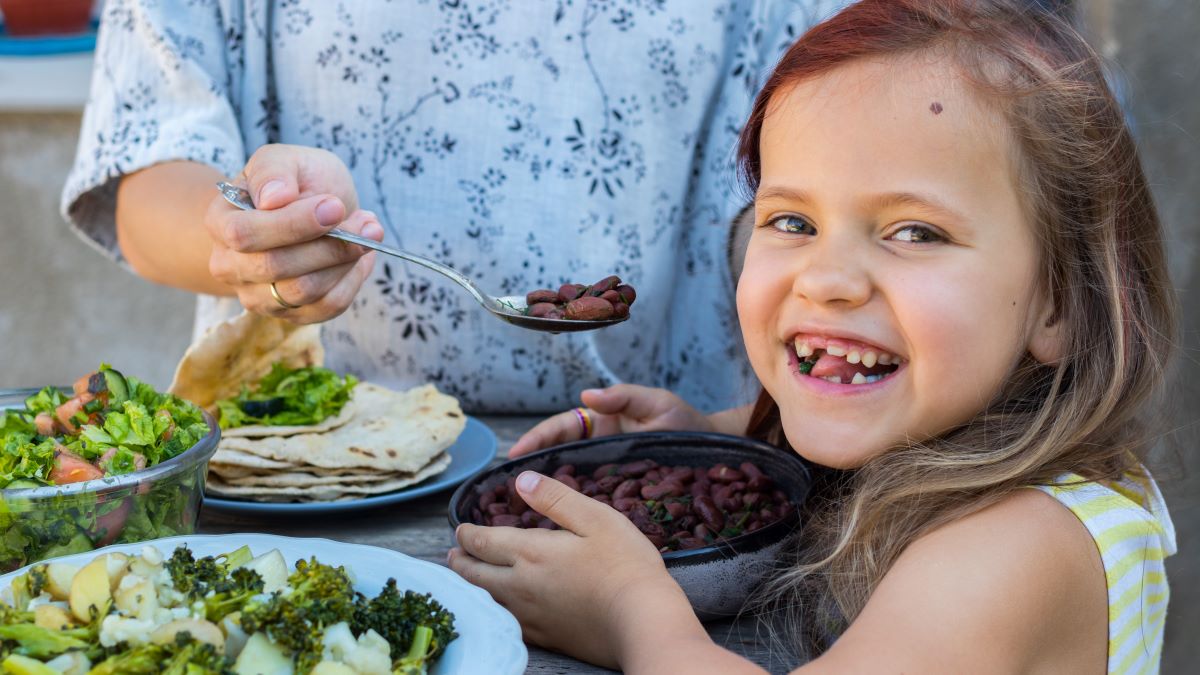 Young girl smiling and eating a vegetarian meal