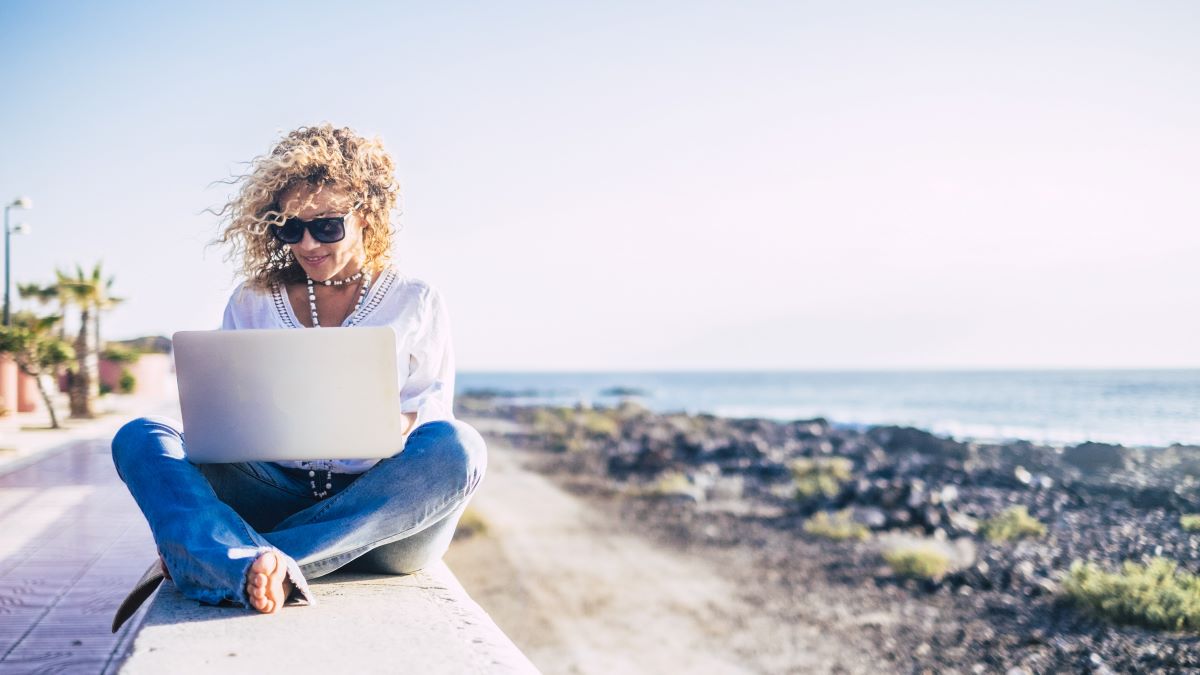 woman using her laptop overlooking the ocean
