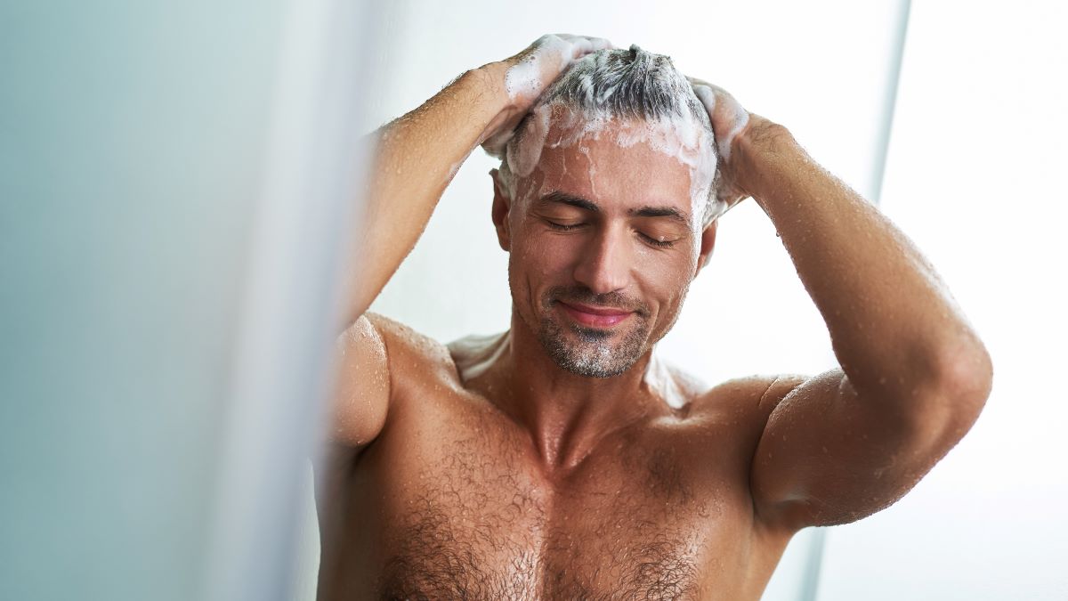 Young man washing his hair in the shower