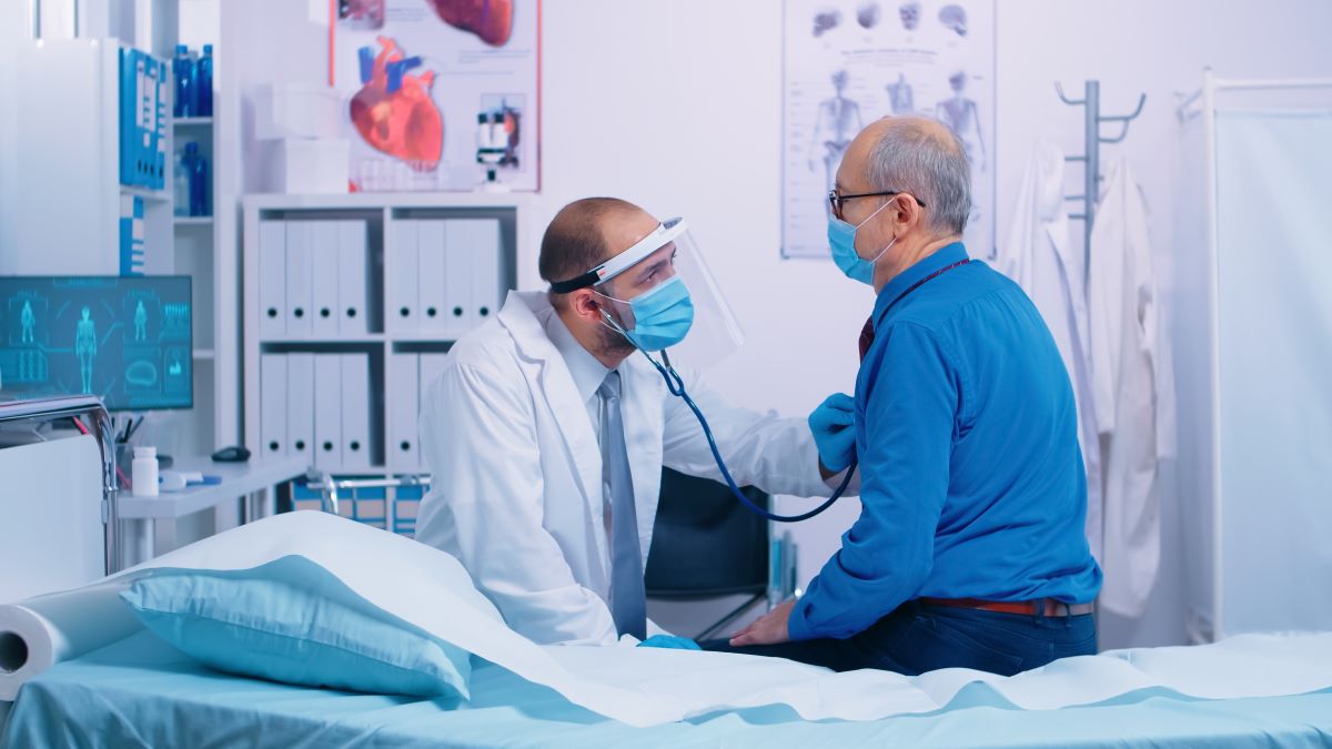 Doctor listening to heart of male patient