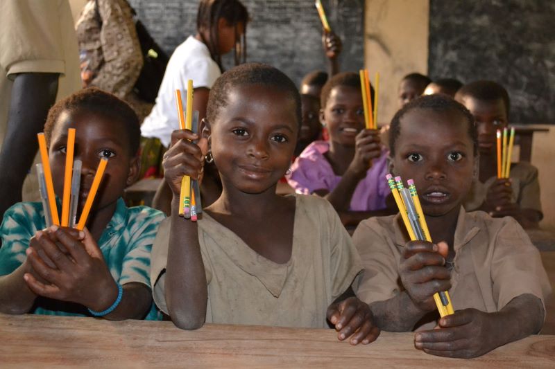 School children holding new pens and pencils
