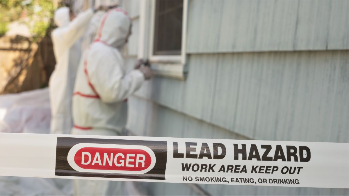 Workers removing hazardous lead paint from house exterior