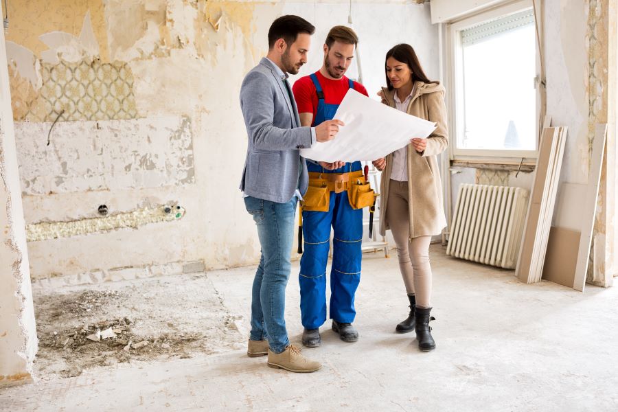 Couple looks at plans for home renovation with worker