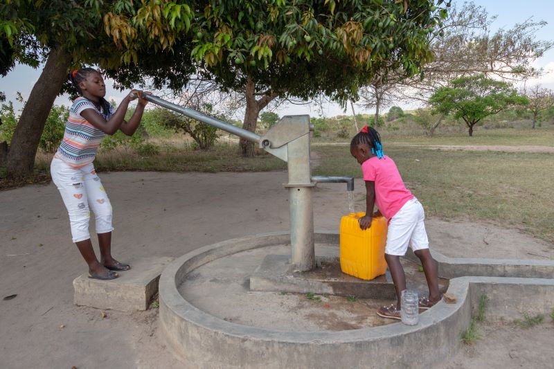 Young girls getting fresh water in the community hand water pump in rural Africa