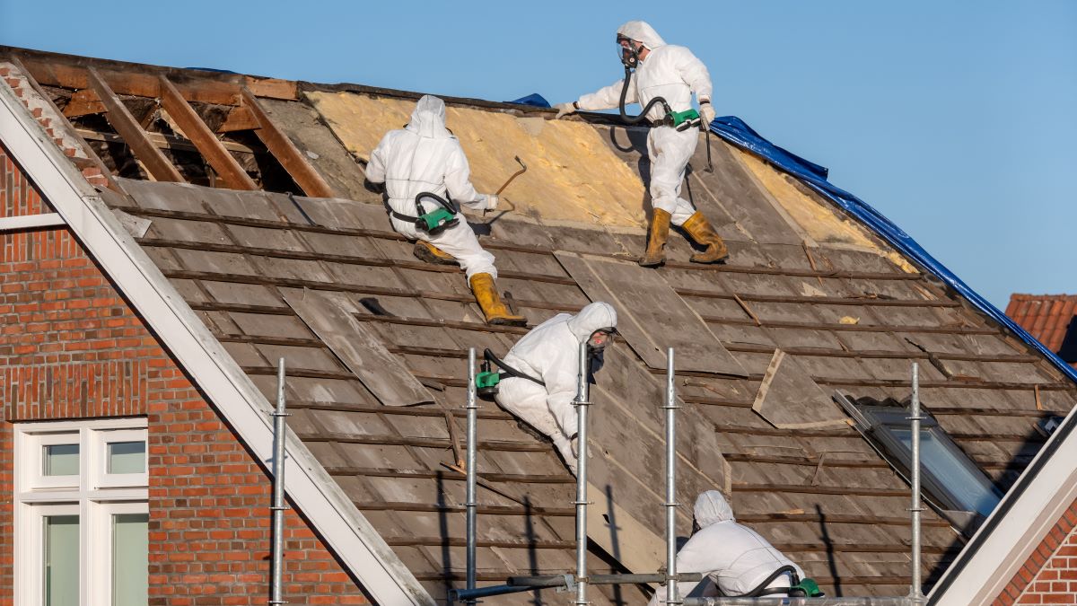 Professionals in suits remove asbestos-cement roofing material