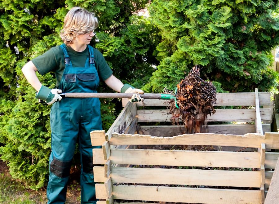 Woman turns compost pile with pitchfork