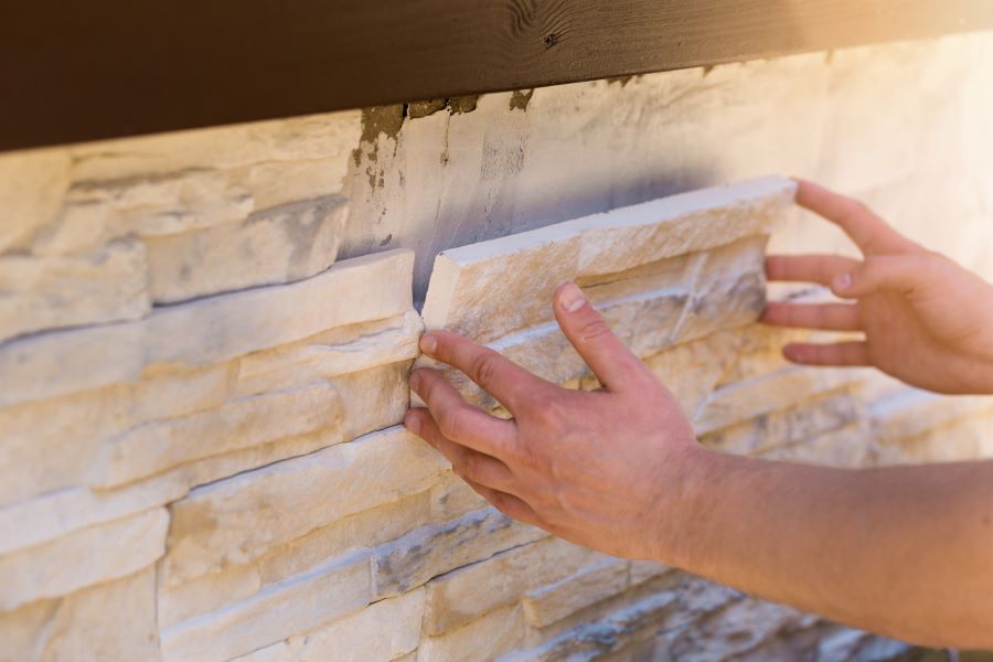 Worker applies stone siding to a house