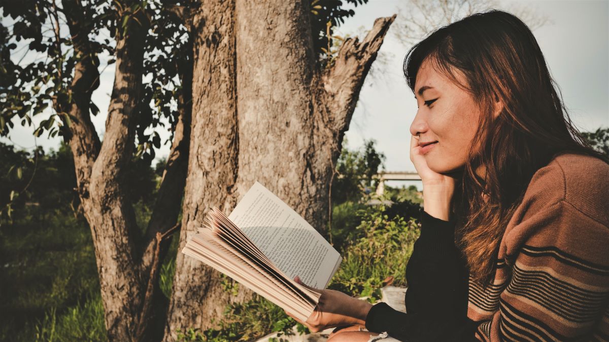 Asian woman reading a book in a natural setting
