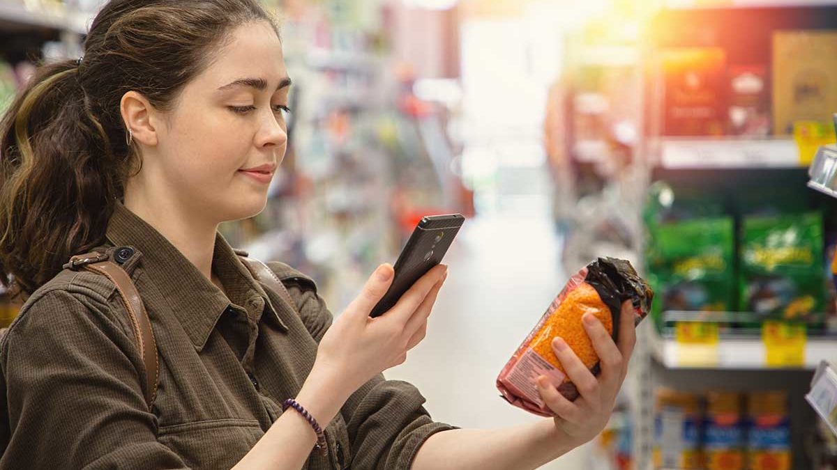 Woman checking label of package with smartphone